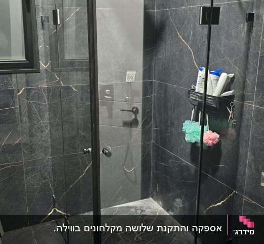 מקלחון פינתי מזכוכית עם פרופילים בשחור בחדר רחצה מעוצב